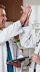 Doctors, people and high five with tablet in clinic for research, digital app or test results. Man, woman and celebration in hospital with tech, medical service report and good news for healthcare