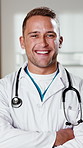 Face, doctor and healthcare with smile at clinic, medical professional and integrity with surgeon. Man, physician or surgical specialist with ambition, pride and happy in medicine with arms crossed