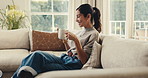 Happy, woman and drinking coffee in home with phone, reading morning news and online blog on weekend. Mature person, smile and typing in living room with tech, tea and mobile app for social media.