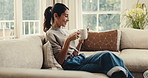 Happy, woman and coffee in home with phone, reading morning news and online entertainment on weekend. Mature person, smile or relax in living room with tech, warm drink or mobile app for social media