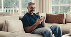 Man, smile and typing in home with phone, social media and online entertainment on peaceful weekend. Happy, mature person and relax in living room with mobile tech, glasses and internet connectivity.