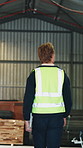 Carpenter, man and walk in factory for inspection, quality control or inventory management. Back, person and check storage for woodwork industry, timber stock and monitor supply chain with tablet