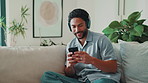 Smile, phone or man with headphones in home for playlist, streaming podcast or typing to search song. Mobile, music and happy person in living room, listening to media or radio on internet to relax