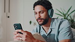 Relax, phone and man with headphones in home for playlist, podcast and streaming song on weekend. Mobile, music and happy person in lounge, typing text message and radio for hip hop on internet