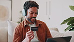 Ecommerce, laptop and happy man with credit card in home, online shopping and relax with headphones. Digital, payment and person with tech, smile and listening to music in lounge or purchase in house