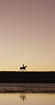 Sunset, silhouette and person with horse for travel, adventure or mockup space by countryside lake. Sky, outdoor and rider on horseback with equine for journey, trip and hobby with pet animal