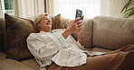 Happy, woman and relax on sofa with phone, check online notification or satisfaction for good news. Mature person, smile and rest in home with tech, text message and stress free on peaceful weekend.