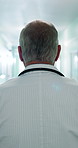 Back, man and doctor walking at hospital, shift arrival and ward rounds for patient care in lobby. Mature person, punctual and medical consultant in hallway, emergency response and healthcare service