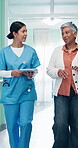Tablet, nurse and senior patient in hospital lobby together with online records, connection and app. Healthcare, technology and happy women walking for discussion, discharge and medical stay review