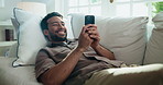 Texting, laugh and man in home with phone, online communication and social media scroll on day off. Digital, happy and person on sofa with tech, message notification and chatting on weekend break.