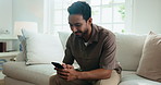 Texting, smile and man in house with phone, online communication and social media scroll on day off. Digital, happy and person on sofa with tech, message notification and chatting on weekend break.