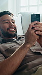 Relax, phone and happy man on sofa for texting, social media forum or internet search on weekend. Mobile, smile and person in home lounge with chat app, communication or contact response with meme