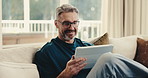 Mature, man and sofa with tablet in home for online streaming, subscription or network connection. Male person, relax and research with smile on technology for entertainment app or game in house