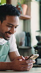 Text, laughing and barista in cafe with phone, funny chat and social media update on work break. Happy, waiter or man in restaurant with tech, hospitality meme or online communication in free time.
