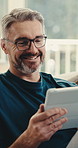Mature, home and happy man with tablet for online streaming, entertainment or subscription. Male person, user or smile with technology on sofa for network connection, research or fun game in house