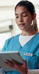 Typing, tablet and medical doctor at clinic for healthcare service, telehealth and communication. Tech, serious and woman with uniform in hospital for guidelines, support and internet for advice