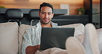 Man, relax and reading on sofa with laptop, streaming and watching trailer of new movie releases. Smile, male person and typing in home with tech, upcoming film and internet search for trending video
