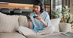 Headphones, phone and woman on sofa with credit card, online shopping purchase and digital banking. Happy, home and person on mobile app with music for payment, transaction and website store sale