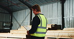 Man, carpenter or inspection with checklist in warehouse for wood production, logistics or distribution. Male person, walking and checking stock or inventory for timber storage or lumber supply chain