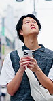 Travel, phone and Asian man in city with digital map, location app and walk outdoor for sightseeing. Tourist, journey and person thinking in urban town with tech, search direction or explore in Japan