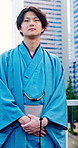 Fashion, tradition or asian man with kimono in city for Japanese culture, style or clothing. Male person, travel and waiting on sidewalk with people walking for commute in Tokyo, Japan or urban town