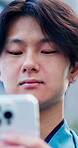 Phone, city and asian man outdoor with internet for travel, social media and search on website. Happy, person and technology with reading, typing online and network connection by bokeh in Japan