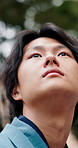 Thinking, sightseeing and asian man with vision in nature for travel adventure or outdoor journey. Thoughtful, male person or daydreaming with wonder for trip, ambition or commute in Tokyo or Japan