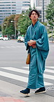 Japanese man, walk and travel with crosswalk, traditional outfit and sandals for heritage or summer fashion. Person, commute and steps for style, culture and trip with casual kimono or yukata in city