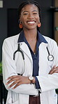 Face, black woman and doctor in hospital with smile, medical advice and cardiologist for wellness. Portrait, surgeon and arms crossed in workplace for cardiology, patient care and healthcare service