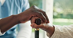 Caregiver, woman and holding hands in home with cane, support or assurance for injury rehabilitation. Nurse, help and person with disability, walking stick and healthcare worker for assisted living.