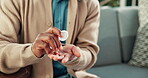 Man, hands and pills with container on sofa for medication, prescription or daily dosage in home. Male person, patient or tablets for pharmaceuticals, medical plan or treatment with supplements
