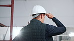 Thinking, helmet and back of man in building for inspection, safety compliance and planning at site. Architecture, construction person with ppe for renovation, remodeling and property evaluation