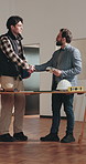 Architect, handshake and teamwork for interior design planning, brainstorming and remodeling. Men, collaboration and shaking hands at worksite with discussion, happy and color swatch for renovation