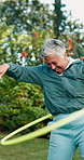 Senior, exercise and happy woman with hula hoop in nature for outdoor workout or activity. Elderly, female person or laughing with spinning ring or training for vitality, health or wellness in park