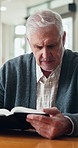 Senior, man and reading with book for knowledge, literature or interesting story in retirement home. Elderly, male person or information with novel for wisdom, history or scripture in old age house
