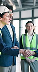 Engineer, handshake and happy people with team, talk and planning for project with tech in building. Civil engineering, agreement and colleagues with tablet, shaking hands and property development