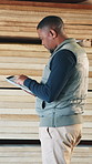 Carpenter, planning and man with wood, tablet and inventory for quality assurance in workshop. Carpentry, woodworking and African person on tech for report, timber production and lumber manufacturing