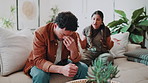 Stress, couple and conflict in home with argument, confrontation and separation of broken trust. Upset, people and jealousy on sofa for disagreement, insecurity and breakdown for infidelity suspicion