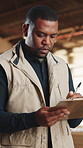 Writing, carpenter and black man with clipboard in warehouse for inspection, planning or agenda. Manufacturing, timber factory and person with checklist for workshop, safety and compliance with stock