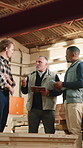 Carpenter, team and talk in factory for manufacturing with checklist, timber stock and tablet review. Men, woodwork and collaboration in meeting for production plan, inventory storage and clipboard
