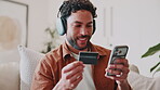 Phone, credit card and man on sofa for payment, online shopping and internet banking with app. Headphones, debit and happy person in home with sign up for financial podcast, savings and investment