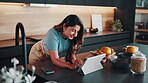 Woman, tablet and scroll n home for remote work, research notes or article with editing in kitchen. Person, technology and smile with website, funny feedback or email for proofreading and WFH
