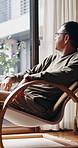 Window, thinking and Asian man relax in apartment with chair, contemplation and calm weekend break. Mature, Japanese person and rest in home with comfortable seat, reflection and peaceful afternoon.