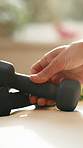 Person, hands and weights with dumbbells in home for exercise, workout or fitness training. Active, equipment or gym gear with iron bars or strength for weightlifting, health or wellness in house