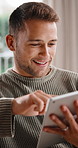 Typing, online and happy man with tablet in lounge, texting or communication with contact on website. Reading, message and person with smile in living room, relax and chatting with technology in home