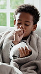 Tissue, fever and child coughing on sofa for recovery of allergy infection, flu or cold. Sneeze, sick and boy with symptoms in living room for healing with illness, sinus or congestion in home