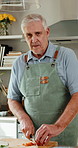 Face, cooking and senior man in kitchen, cut carrots and happy with natural healthy food. Smile, chopping board and person with vegetables at home for meal prep, nutrition or vegan diet in retirement