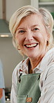 Mature, face and happy woman with pride in kitchen for cooking, hospitality or meal prep in home. Portrait, female person or chef with apron, smile or welcome for culinary art or skill in house