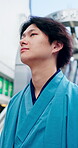 Thinking, windy and yakata with Asian man in city for commute, journey or traditional clothing. Culture, ideas and outfit with Japanese traveler outdoor in urban town for break, trip or vision