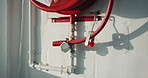 Building, safety and fire hose reel on wall for protection, compliance and emergency access. Pipe, firefighting equipment and outdoor installation for hazard prevention, water supply and regulations